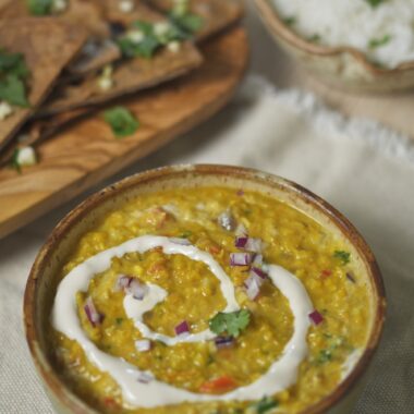 bowl of immune boosting flu fighter dal soup with chapati and rice in background