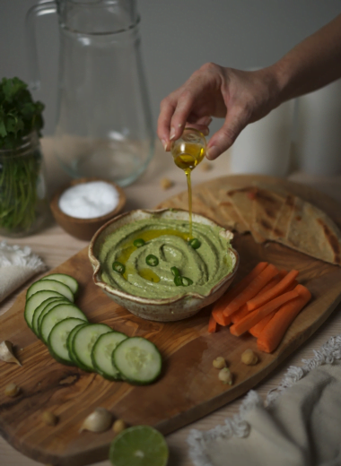 cilantro serrano hummus being topped with evoo