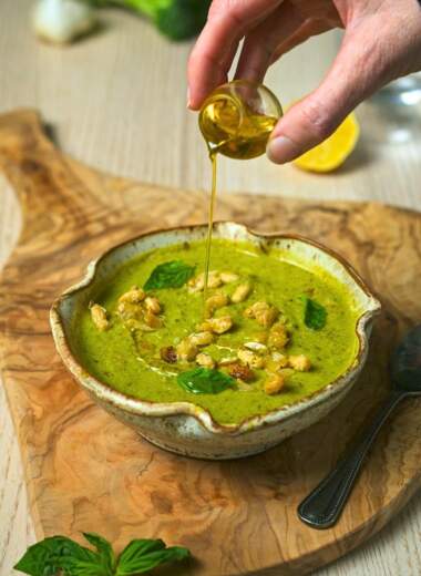 Drizzling olive oil over creamy pesto soup.
