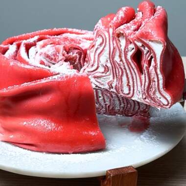 Taking slice of rose crepe cake.